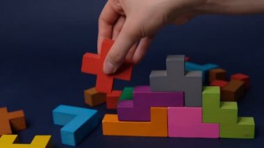 Yakın çekim Ağır çekim. Elle tutulan tahta yapboz parçası. Ahşap küp yığını. Karmaşık ve mantıklı düşünme kavramı. Siyah bir arkaplanda