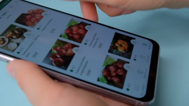 RÚSSIA, Moscou - JANEIRO 2020. Smart phone compras online. Mulher pede comida para casa em uma loja online usando um smartphone. Feminino seleciona as maçãs de frutas na mercearia loja online. Close-up . — Vídeo de Stock