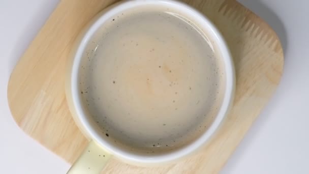 Espuma de café gira em xícara branca com café. sobre fundo branco. Fechar câmara lenta. Vista de cima para baixo. Café da manhã de uma xícara de café preto quente no fundo branco . — Vídeo de Stock