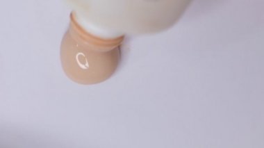 Yüz için temel izleri var. Kozmetik lekesi. Beyaz arka planda izole edilmiş. Temelde makyaj lekesi, leke. Kozmetik sıvı temel ya da pansiyon krem bej. Yakın çekim Yavaş çekim.