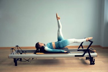 Leotard egzersiz pilates eğitimi. Atletik pilates yenilikçi egzersizleri. Pilates makinesi ekipmanı. Genç Asyalı kadın bir stüdyoda esneme sporu yapıyor.