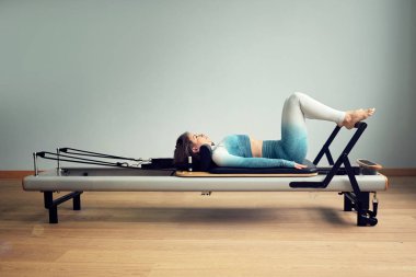 Leotard egzersiz pilates eğitimi. Atletik pilates yenilikçi egzersizleri. Pilates makinesi ekipmanı. Genç Asyalı kadın bir stüdyoda esneme sporu yapıyor.