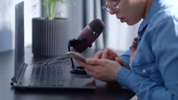 Portret młodej blogerki prowadzącej transmisję na żywo, przemawia do micraphona. kobieta prowadzi podcast w domu przed laptop — Wideo stockowe