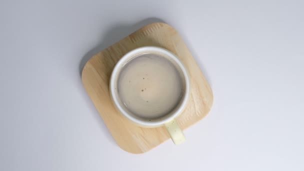 La schiuma di caffè gira in tazza bianca con caffè. su sfondo bianco. Primo piano Rallentatore. Vista dall'alto. Colazione mattina di una tazza di caffè nero caldo su sfondo bianco . — Video Stock