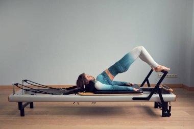 Leotard egzersiz pilates eğitimi. Atletik pilates yenilikçi egzersizleri. Pilates makinesi ekipmanı. Genç Asyalı kadın bir stüdyoda esneme sporu yapıyor.