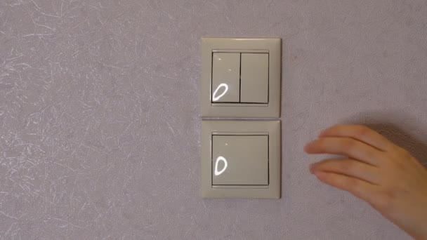 Свет выключен - женская рука выключает кнопку на светло-серой стене, вид спереди — стоковое видео