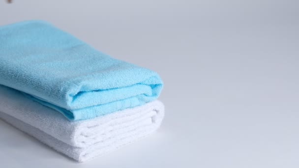 White and blue clean towels and a cotton branch on a white background. Closeup Slow motion. — Stock Video