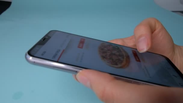 Russland, moskau - januar 2020. frau bestellt pizza über online lieferdienst mit smartphone. Nahaufnahme. Frau bestellt Lebensmittel im Online-Shop per Smartphone — Stockvideo