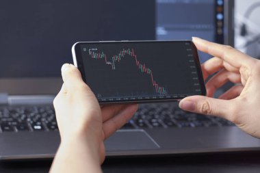 Akıllı telefonlardan hisse senedi alım satımı yapan bir kadın. İş konsepti. İş kadını eliyle akıllı telefondan ticaret yapmak
