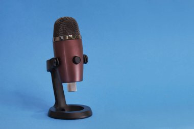 Mavi arka planda modern mikrofon, mavi renkte izole edilmiş.
