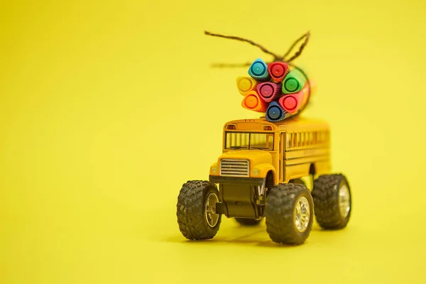 Autobus scolaire jaune et stylos feutre sur le toit, concept de retour à l'école, fond jaune, espace de copie. l'éducation. isolé sur fond jaune — Photo