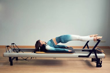 Leotard egzersiz pilates eğitimi. Atletik pilates yenilikçi egzersizleri. Pilates makinesi ekipmanı. Genç Asyalı kadın bir stüdyoda esneme sporu yapıyor.