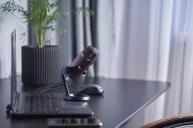 Bilgisayar, akıllı telefon, siyah bir masada mikrofon. Podcast 'i yönetmek üzere olan bir blogcunun konsept çalışma yeri.