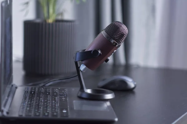 Laptop, smartphone, micrófono en una mesa negra. concepto de lugar de trabajo de un blogger que está a punto de liderar un podcast . — Foto de Stock