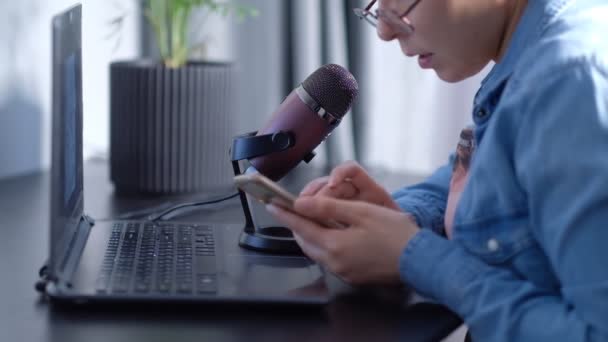 Retrato de una joven blogger conduciendo una transmisión en vivo, habla en un micrafón. mujer lleva podcast en casa delante de la computadora portátil — Vídeos de Stock