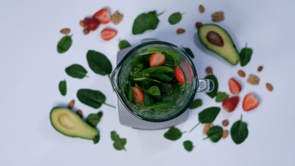 Smoothie vert sain mélangé avec un mélangeur. épinards et avocat sur fond blanc vue de dessus. Gros plan sur la cuisson au ralenti . — Video