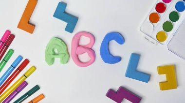 Beyaz arka planda keçeli kalemler, küpler, boyalar ve plastikler. Çocuklar masaüstü bilgisayarı. Okul, eğitim ve öğrenme konsepti. Çocuklar için yaratıcılık. Üst görünüm renkli arkaplan. Düz yatıyordu