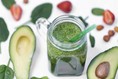 Sağlıklı vejetaryen yeşil ıspanaklı meyve suyu. Beyaz arka planda ıspanak ve avokado. Yavaş çekimde pişirmeye yakın.