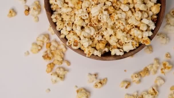 Popcorn in einer hölzernen Schüssel auf weißem Hintergrund. Zeitlupenvideo. Nahaufnahme von oben — Stockvideo