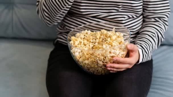 Kobieta zbierająca popcorn z papierowego wiadra. Blisko kobiety jedzącej popcorn w kinie. Koncepcja filmowego jedzenia. Kobieta bierze popcorn. niskokaloryczna przekąska — Wideo stockowe