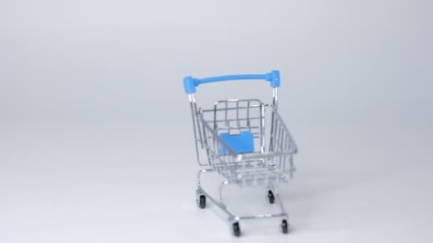 Shopping leksak vagn på vit bakgrund med lite kopieringsutrymme. online shopping koncept Närbild Slow motion. — Stockvideo