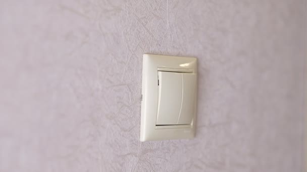 La luz está apagada - la mano femenina apaga un botón en una pared gris claro, vista frontal — Vídeos de Stock