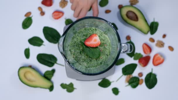 Friska gröna smoothie blandas med en mixer. spenat och avokado på en vit bakgrund ovanifrån. Närbild av matlagning i slow motion. — Stockvideo
