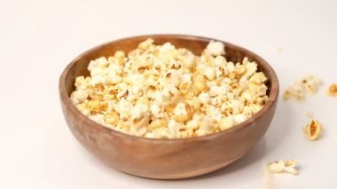 Beyaz arka planda tahta bir kaseye atılmış patlamış mısır. Slow Motion videosu. Üst görünümü kapat