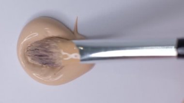 Yüz için temel izleri var. Kozmetik lekesi. Beyaz arka planda izole edilmiş. Temelde makyaj lekesi, leke. Kozmetik sıvı temel ya da pansiyon krem bej. Yakın çekim Yavaş çekim.