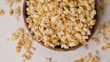 Beyaz arka planda tahta bir kaseye atılmış patlamış mısır. Slow Motion videosu. Üst görünümü kapat