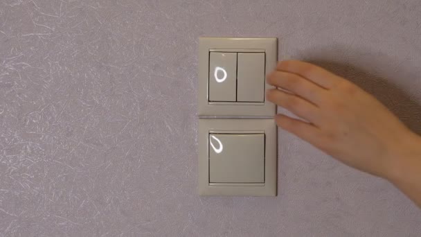 Licht uit - vrouwelijke hand zet een knop op een lichtgrijze muur uit, vooraanzicht — Stockvideo