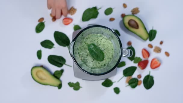 Smoothie verde saudável misturado com um liquidificador. espinafre e abacate em um fundo branco vista superior. Close-up de cozinhar em câmera lenta . — Vídeo de Stock