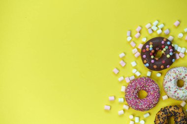 Sarı arka planda donut ve marşmelov. en üstteki resim