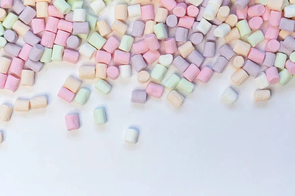 Вид сверху на пастельные конфеты маршмаллоу с некоторой скатертью на бледно-белом столе — стоковое фото