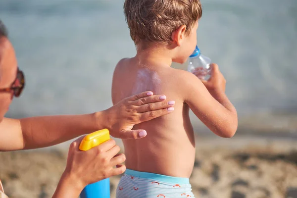 Mom smears her baby skin sun cream on beach. sunscreen. — Stock Photo, Image