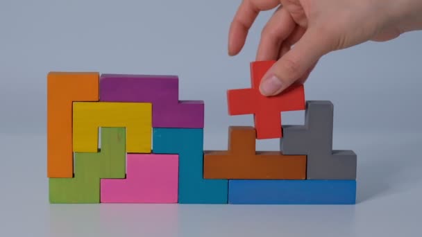 スローモーションを閉じます。手の木のブロックパズルのピースを保持。木製のキューブ積層複雑でスマートな論理的思考の概念. — ストック動画