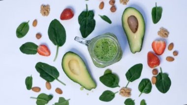 Sağlıklı vejetaryen yeşil ıspanaklı meyve suyu. Beyaz arka planda ıspanak ve avokado. Yavaş çekimde pişirmeye yakın.