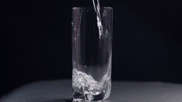studio shoot d'eau coulant dans du verre transparent sur fond noir. Vidéo de ralenti. Vue rapprochée du dessus 