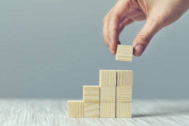 Tahta sehpanın üzerinde merdiven olarak tahta blokları diziyorum. Büyüme süreci için iş konsepti. Boşluğu kopyala