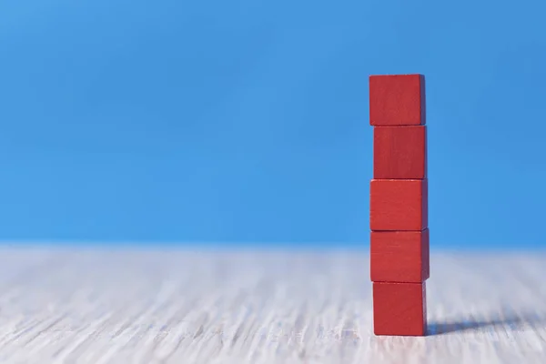 red wood bricks tower. construction from wooden cubes. on a blue background