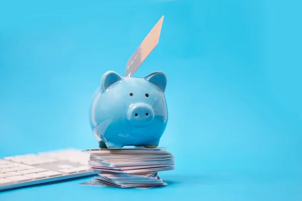 Sparschwein und Haufen von Kreditkarten, finanzielle Verschwendung. Umschuldung, Finanznot, Neuverhandlung der Schulden. auf blauem Hintergrund — Stockfoto