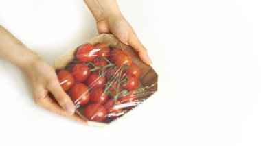 Beyaz bir masada yemek depolamak için yemek filmi kullanan bir kadın. Ürünleri paketlemek için şeffaf polietilen gıda filmi rulosu.