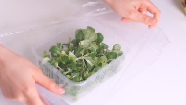 Frau verwendet Lebensmittelfolie zur Lagerung von Lebensmitteln auf einem weißen Tisch. Rolle aus transparentem Polyethylen für Lebensmittelverpackungen. Zeitlupenvideo. Nahaufnahme — Stockvideo