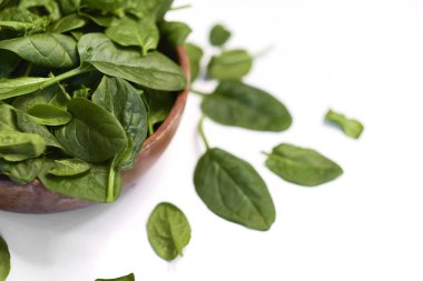 Beyaz arka planda izole edilmiş ahşap bir kasede taze ıspanak.