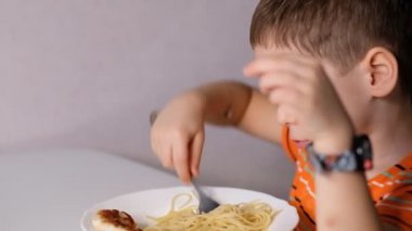 child playing with pasta at dining table. messy face eating. sauce and kid. boy eats pasta noodles sitting in nursery cafe. Happy child eating healthy organic and vegan food in restaurant.
