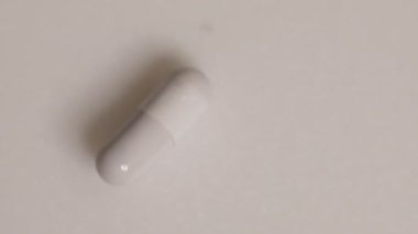 Yavaş çekim videosu beyaz arka plana yavaş çekimde düşen farklı tipte haplar. Çok renkli tabletler uçuyor. Masada çok güzel haplar var. Tıbbi görüntüler, sağlıklı yaşam tarzı