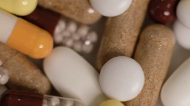 Yavaş çekim videosu beyaz arka plana yavaş çekimde düşen farklı tipte haplar. Çok renkli tabletler uçuyor. Masada çok güzel haplar var. Tıbbi görüntüler, sağlıklı yaşam tarzı