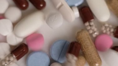 Yavaş çekim videosu beyaz arka plana yavaş çekimde düşen farklı tipte haplar. Çok renkli tabletler uçuyor. Masada çok güzel haplar var. Tıbbi görüntüler, sağlıklı yaşam tarzı