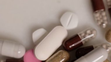 Yavaş çekim videosu beyaz arka plana yavaş çekimde düşen farklı tipte haplar. Çok renkli tabletler uçuyor. Masada çok güzel haplar var. Tıbbi görüntüler, sağlıklı yaşam tarzı