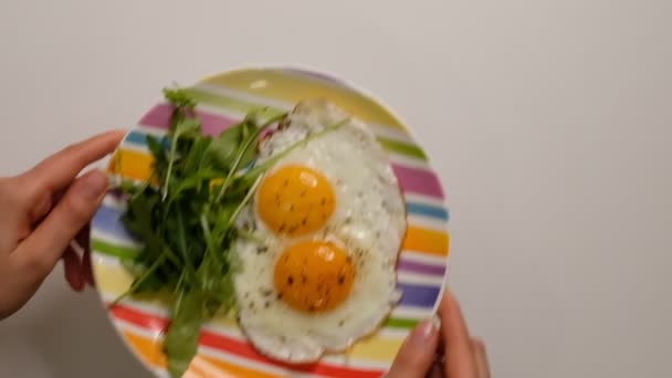 Två stekta ägg på tallriken. Stoppplatta med stekta ägg på träbord. Närbild vit porslinsplatta med stekt ägg. Traditionell frukostmåltid — Stockvideo